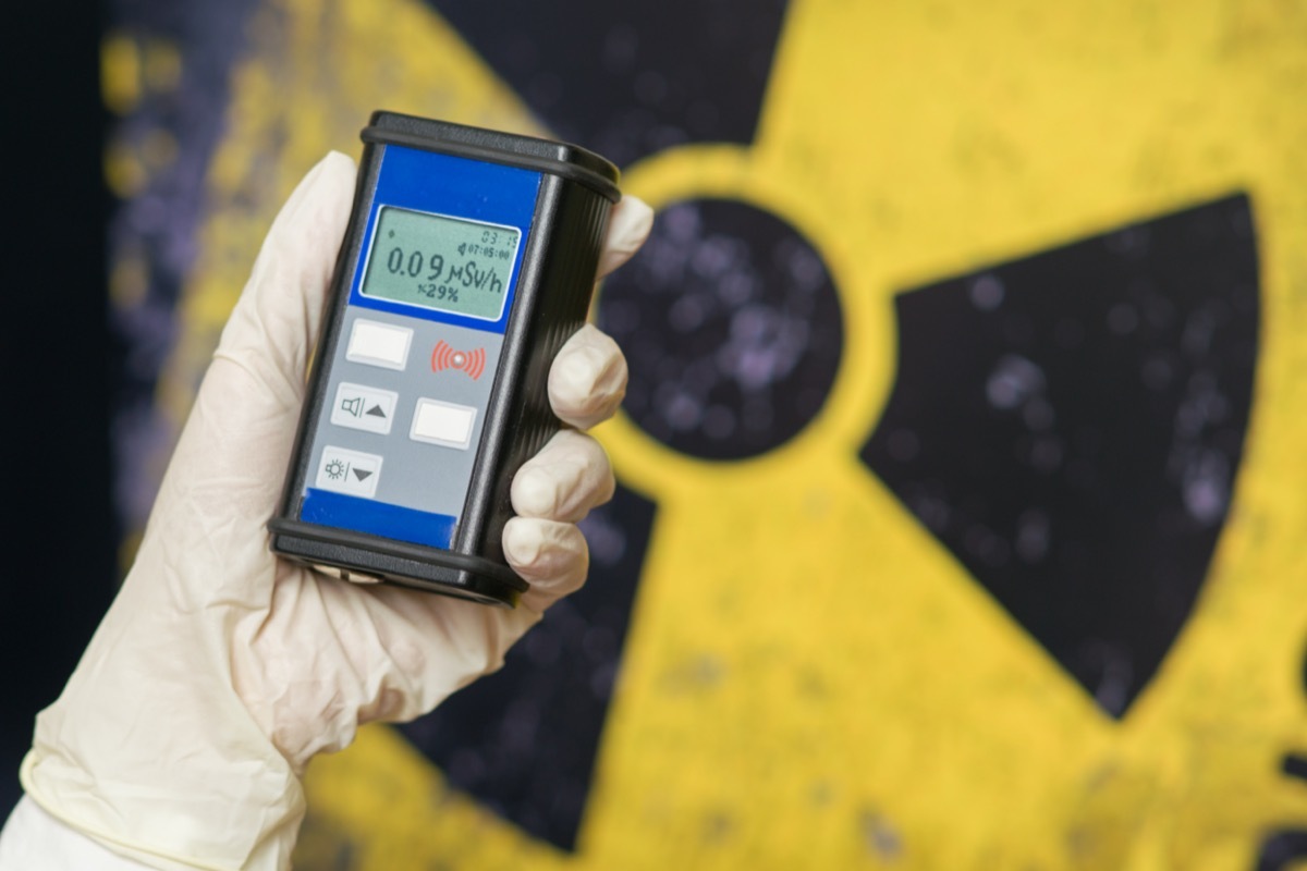 Radiation supervisor in glove with geiger counter checks the level of radiation in the radioactive zone.