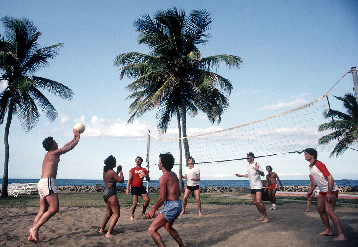 a group of friends play beach volleyball