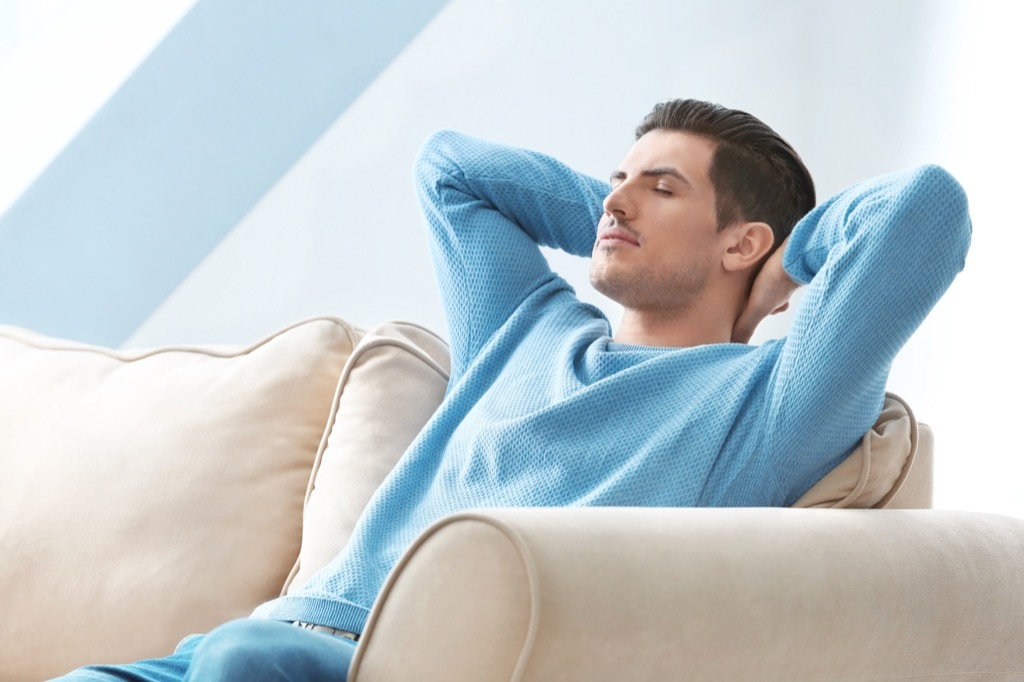 man in blue sweater relaxing on couch