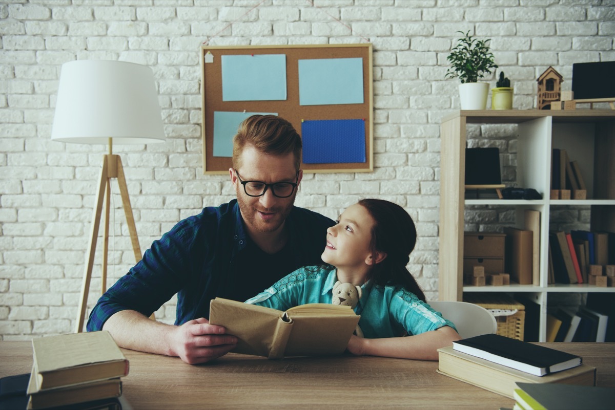 white father reading book with daughter