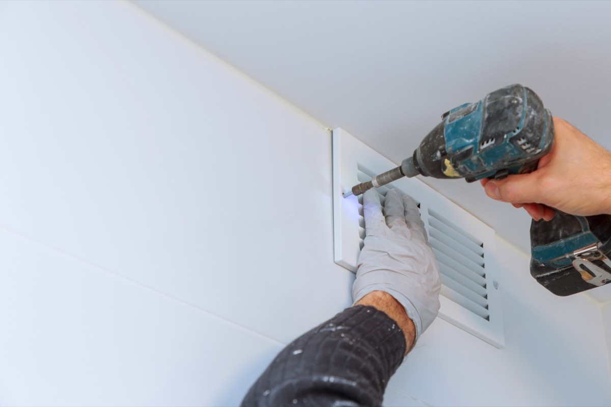 Close up man hand installing vent cover from ceiling Mounted Air Conditioner.