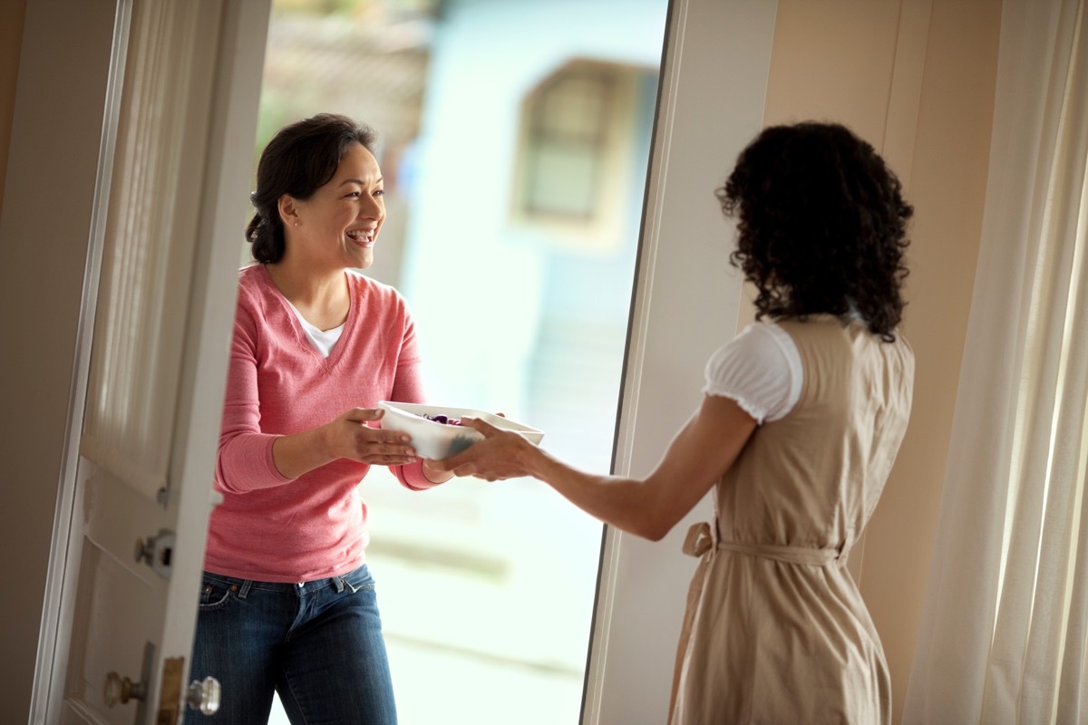 woman delivering casserole dish to friend