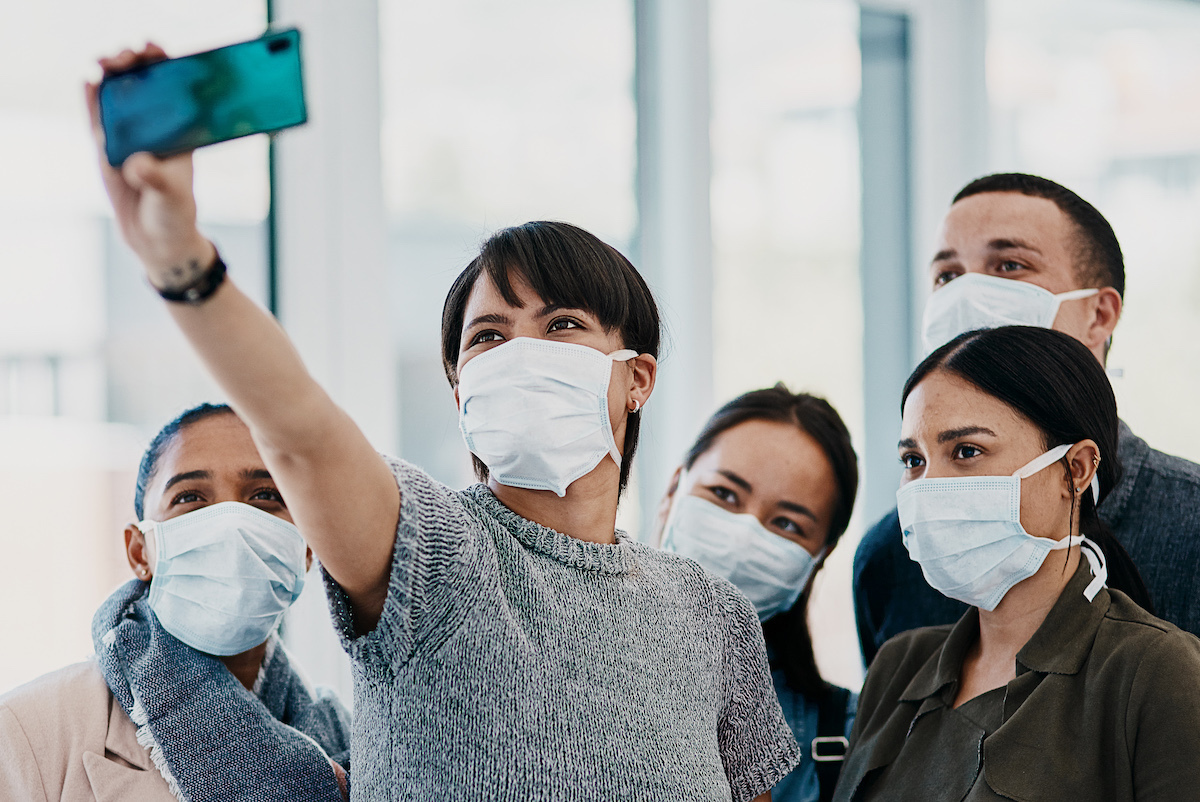 Shot of a group of young people wearing masks and taking selfies at the airport