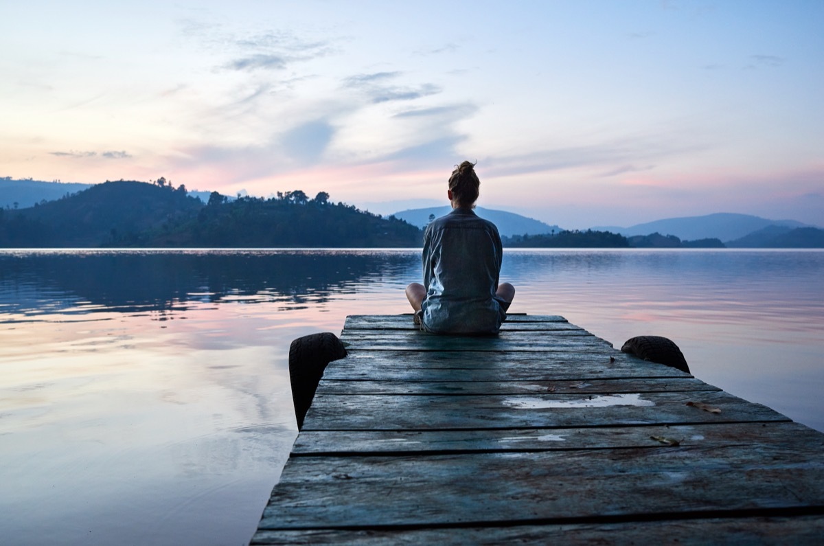 woman sitting on dock looking at lake