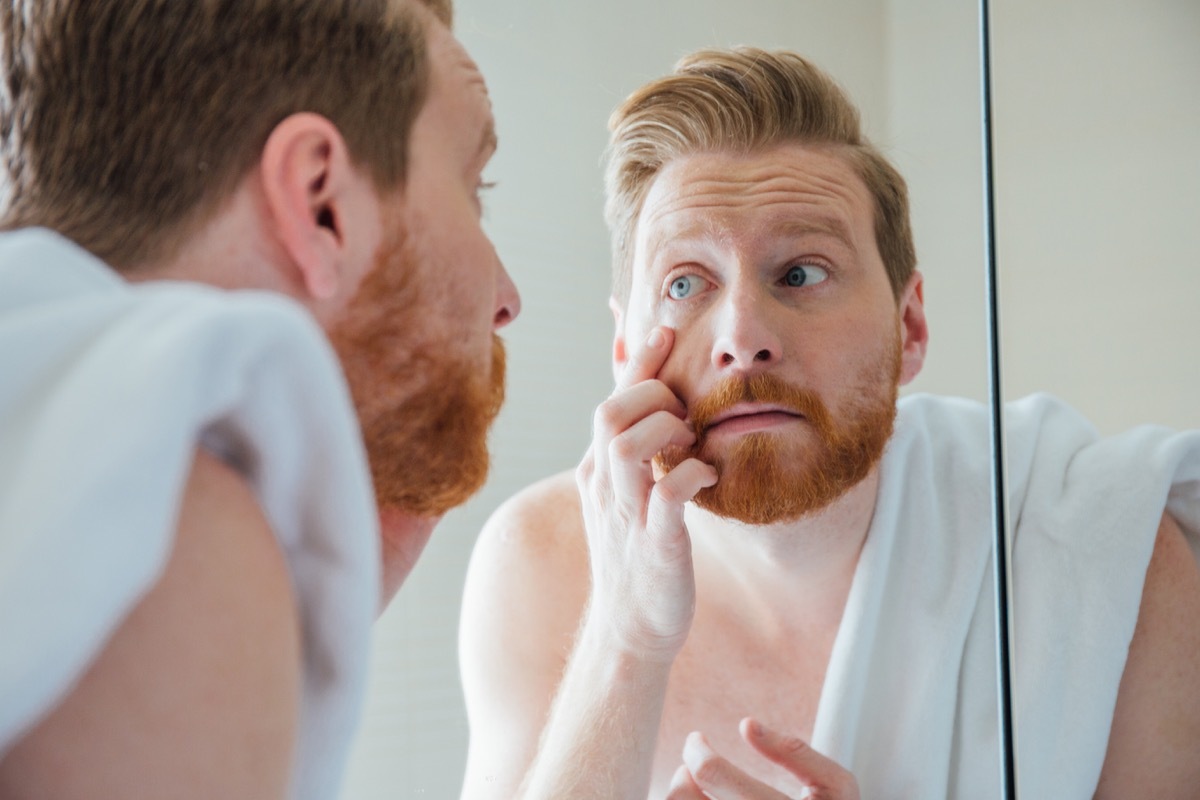 Young man doing home eye exam in the bathroom