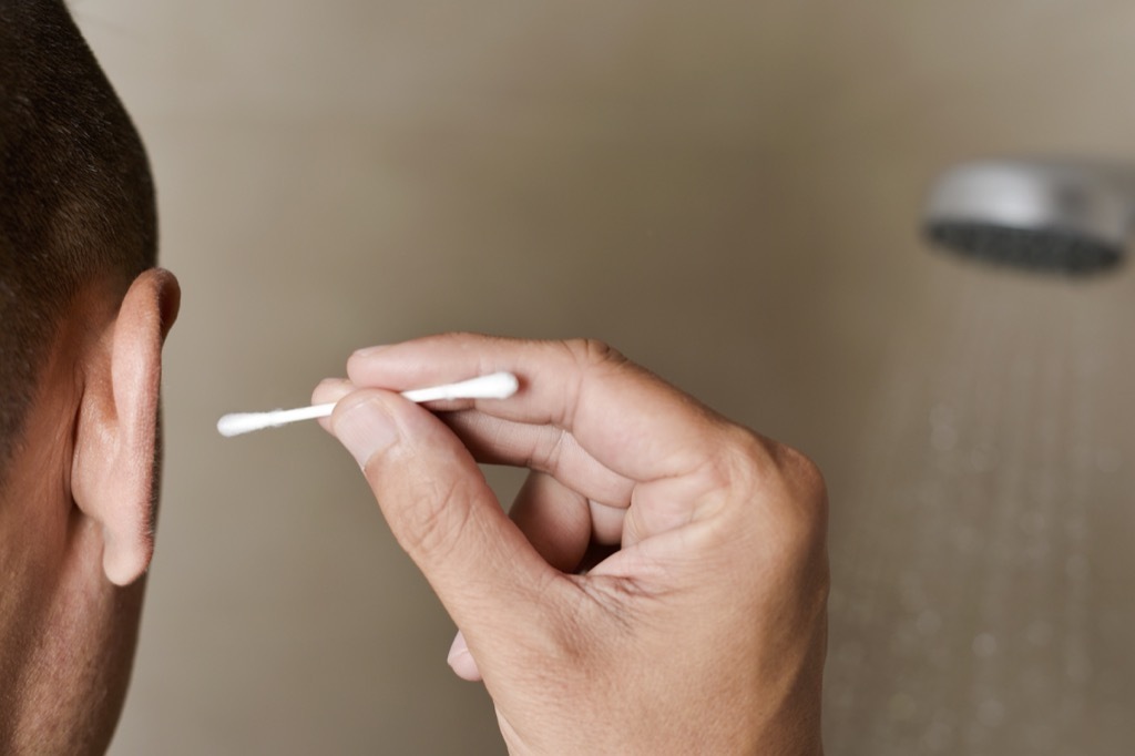 Man cleaning out his ear with a q tip