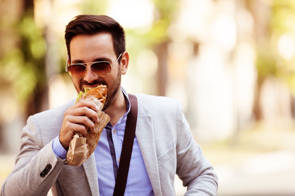 Walking in the city while eating a sandwich.