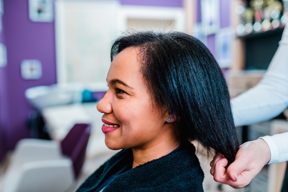 woman on a curly hair straightening treatment at a hair salon.