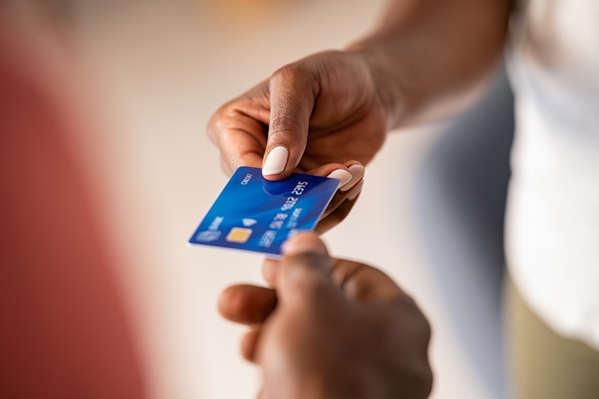 Close up hands of a woman giving bank credit card to man. 