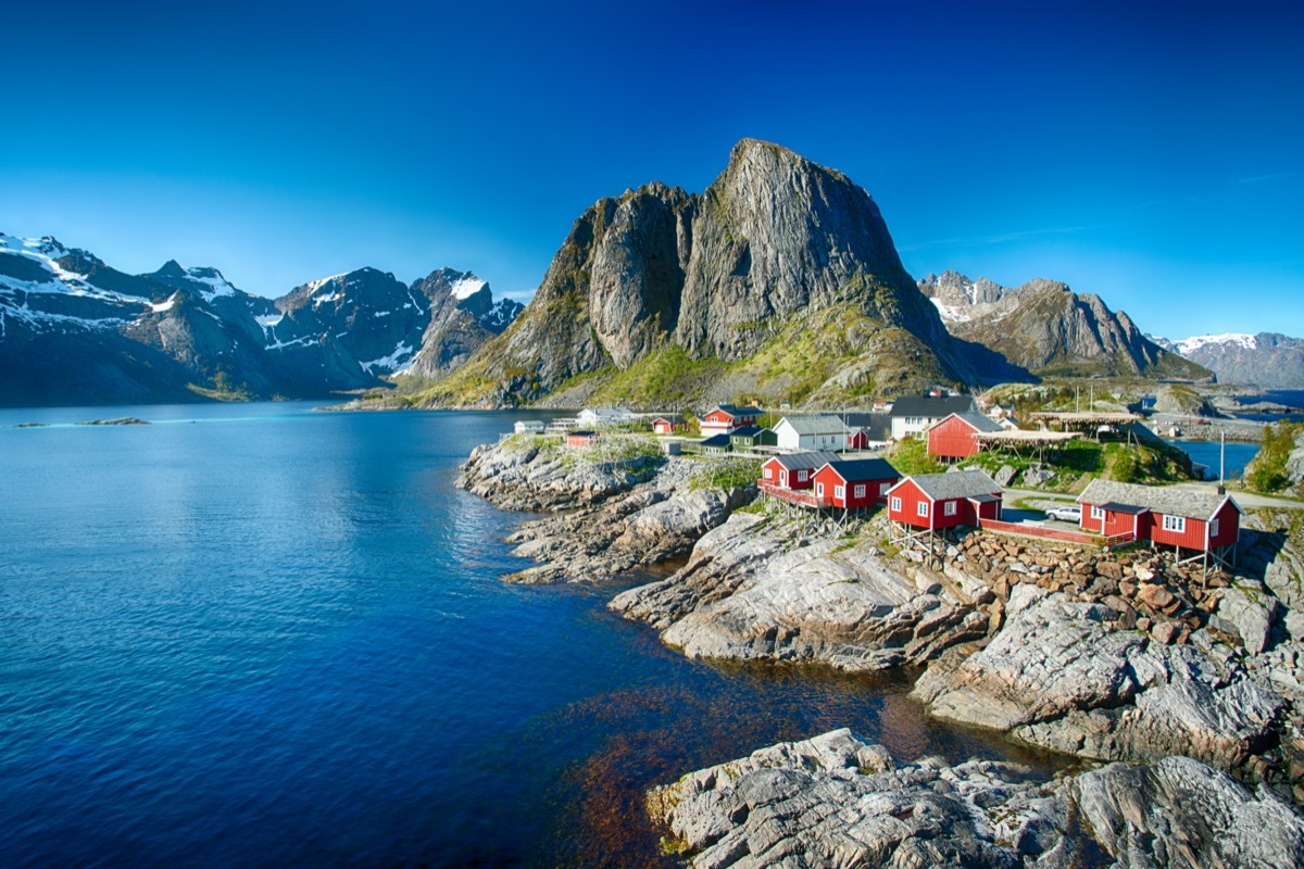 The village of Reine under a sunny, blue sky, with the typical red rorbu houses