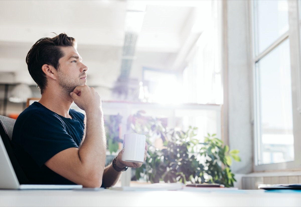 young businessman with coffee in hand sitting at his desk