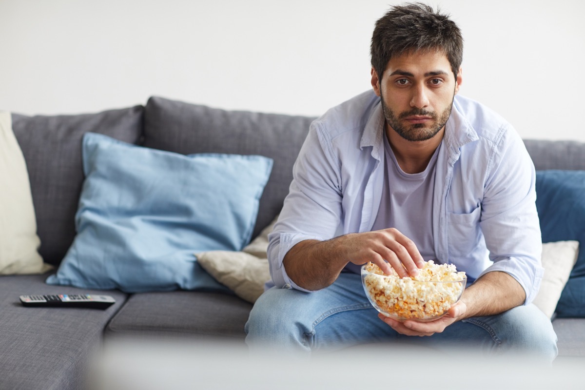 man eating popcorn while watching TV