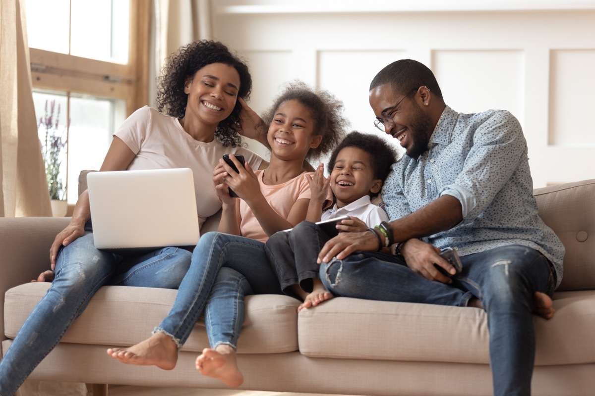 Family laughing on couch together