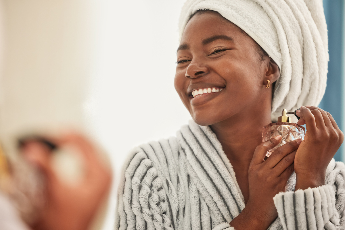 Woman in bathrobe spritzing perfume