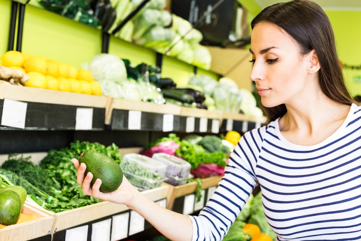 young woman in striped shirt holding avocado