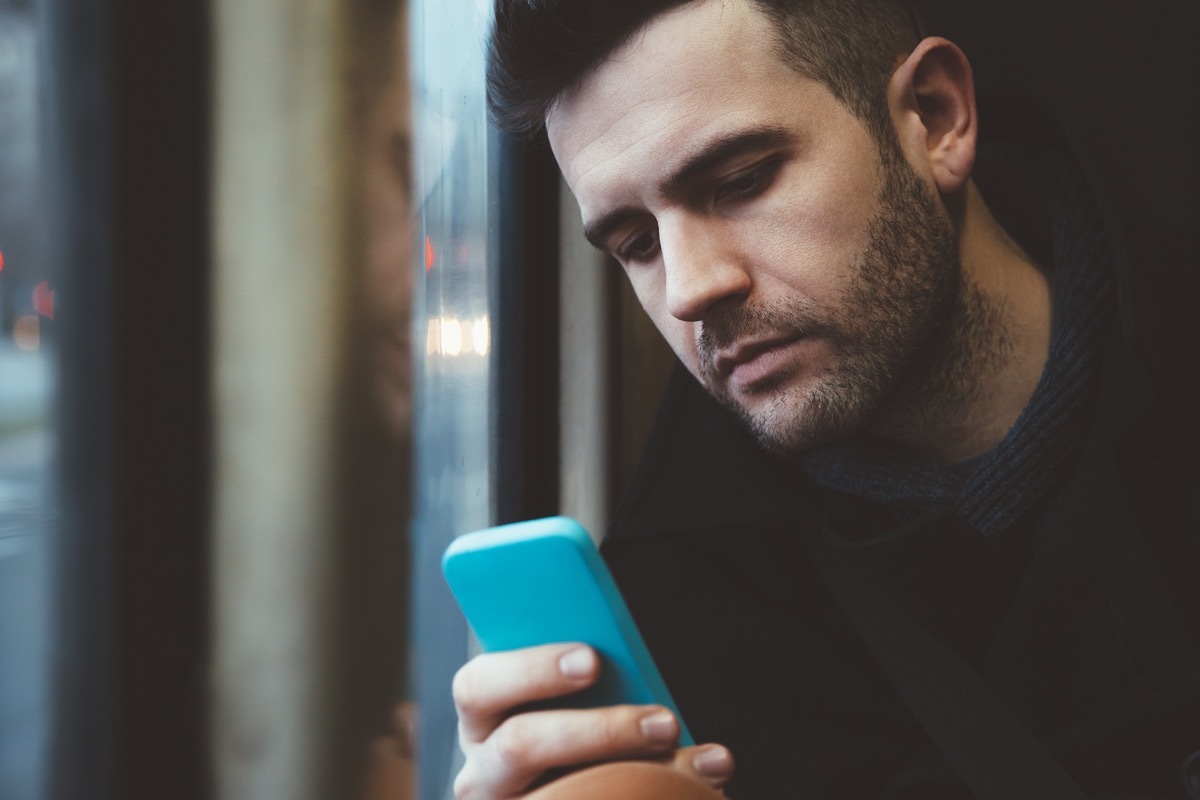 man using a smart phone in the streetcar