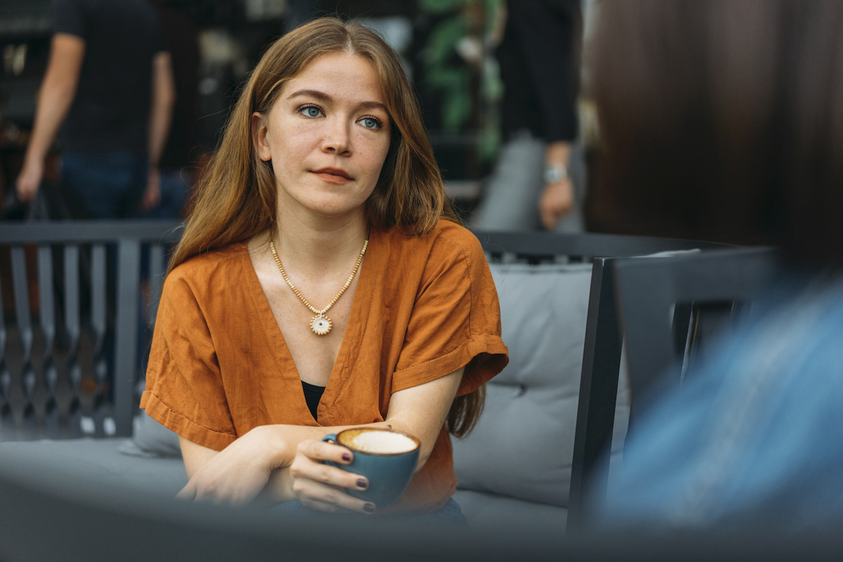 Concerned young woman talks with friend in coffee shop