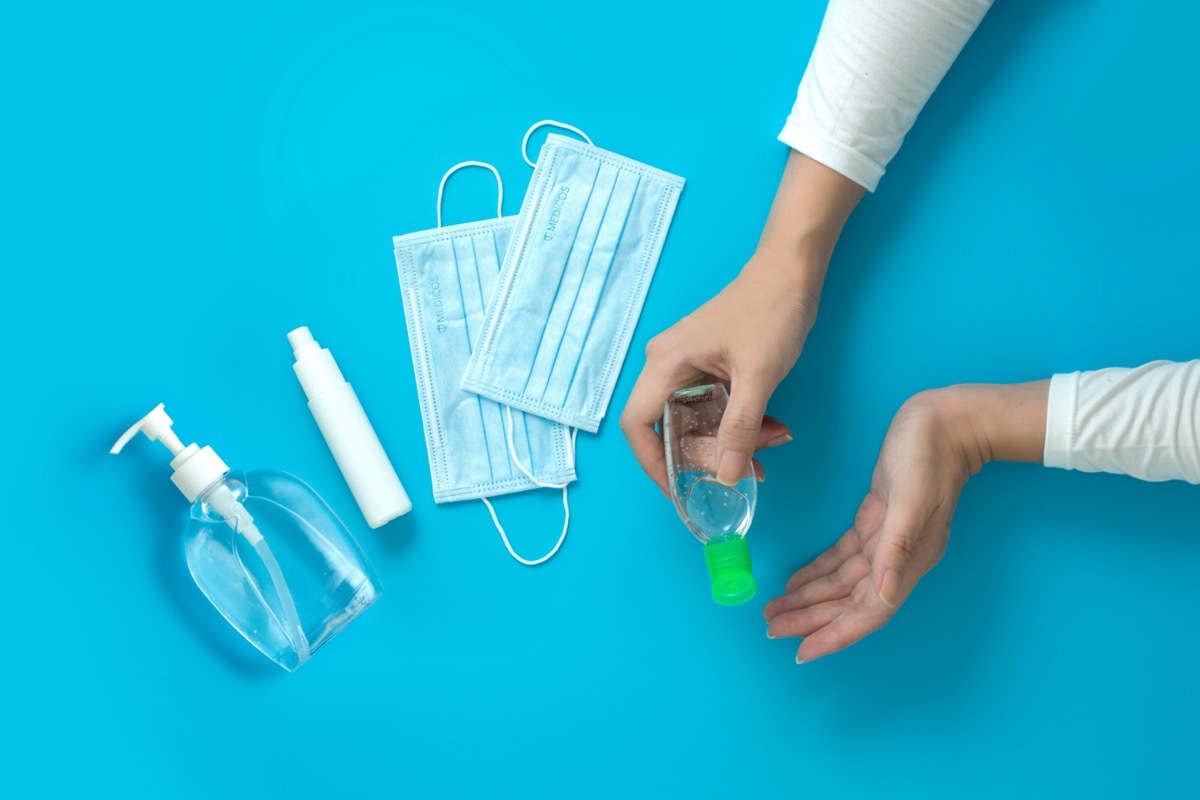 Women hands holding hand sanitizer with alcohol spray and surgical mask.