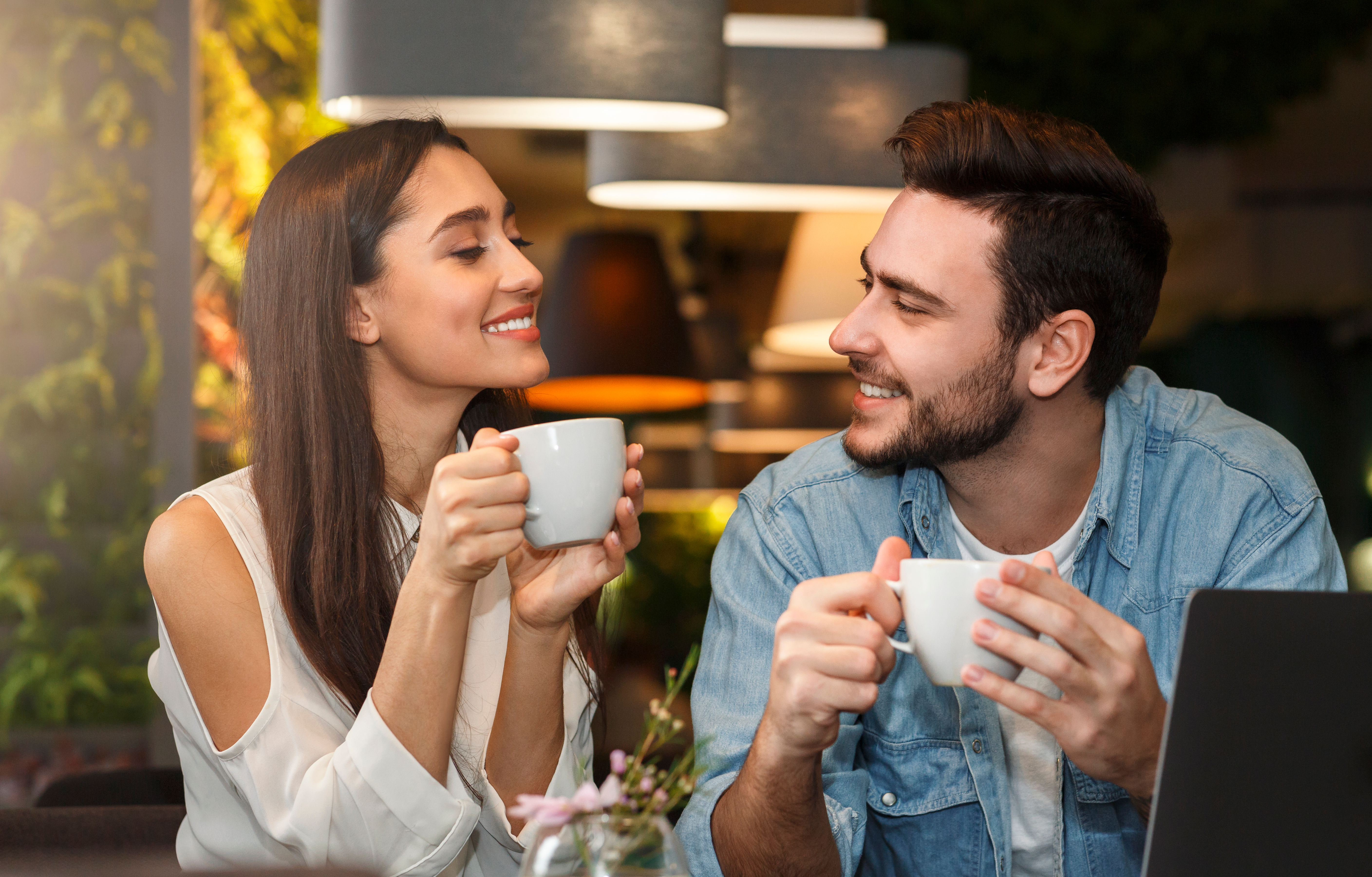 woman at a cafe drinking coffee and asking her boyfriend cute questions