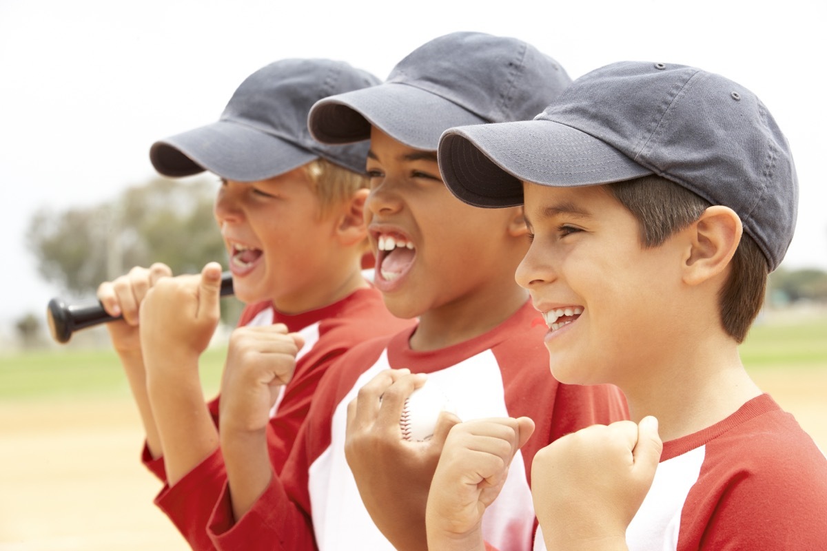 young boys in baseball hats cheering during a game