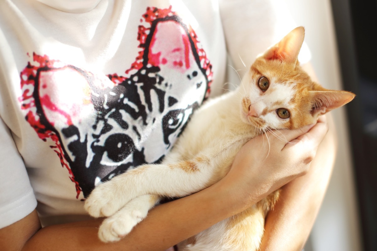 white woman cradling orange cat