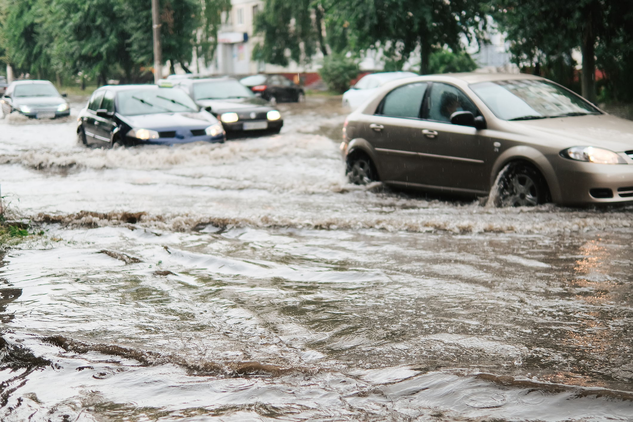 Cars driving down a flooded street