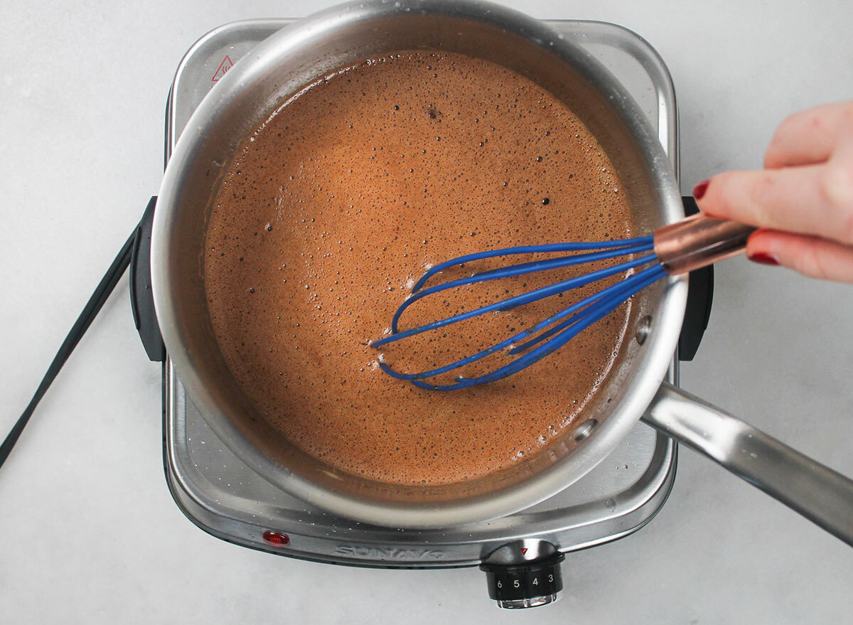 whisking together ingredients for coca cola cake in a pot on the stove