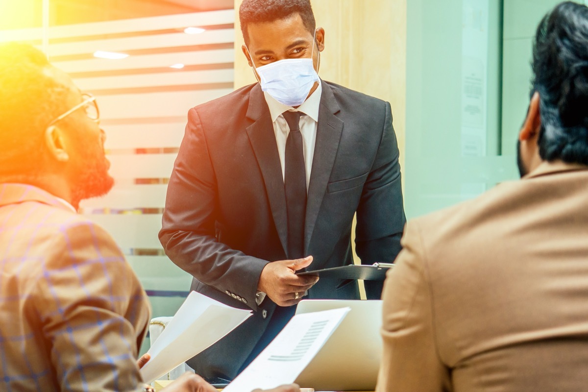 young black businessman wearing mask in meeting amid coronavirus pandemic