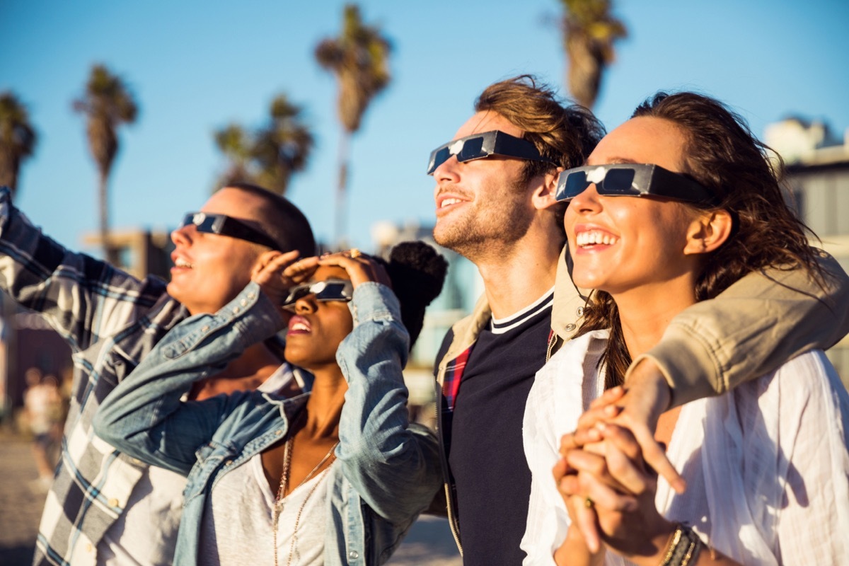 A group of friends watching a solar eclipse with protective glasses on