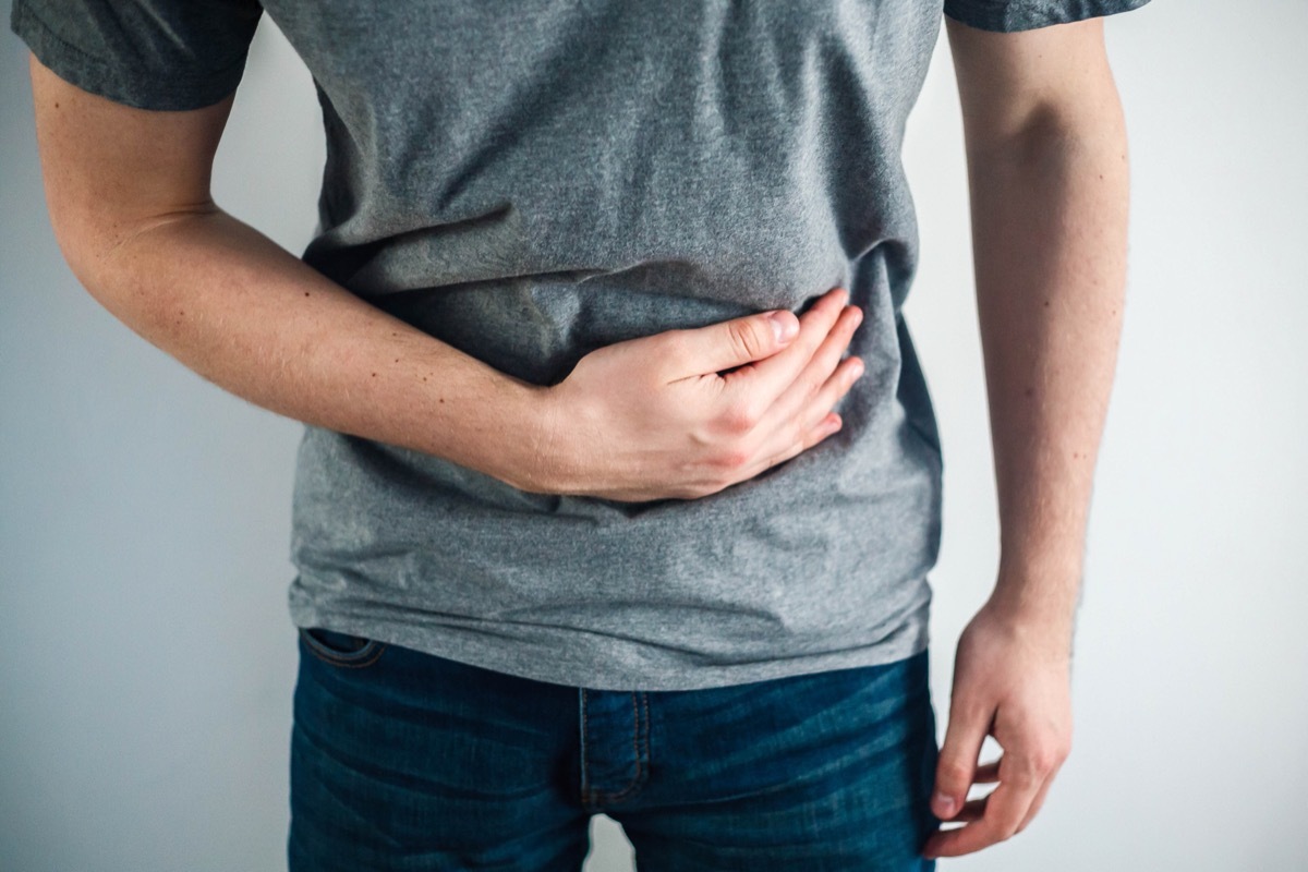 man in gray shirt holding stomach