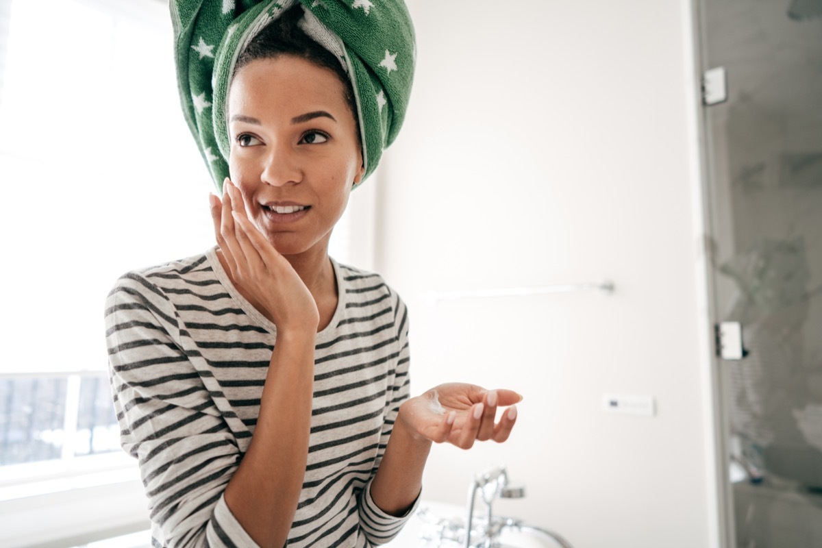 woman applying moisturizer after getting out of the shower