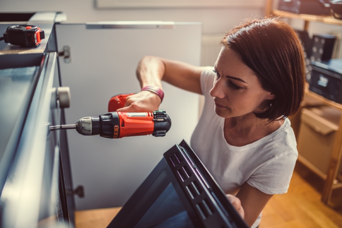 woman drilling into kitchen appliance, increase home value