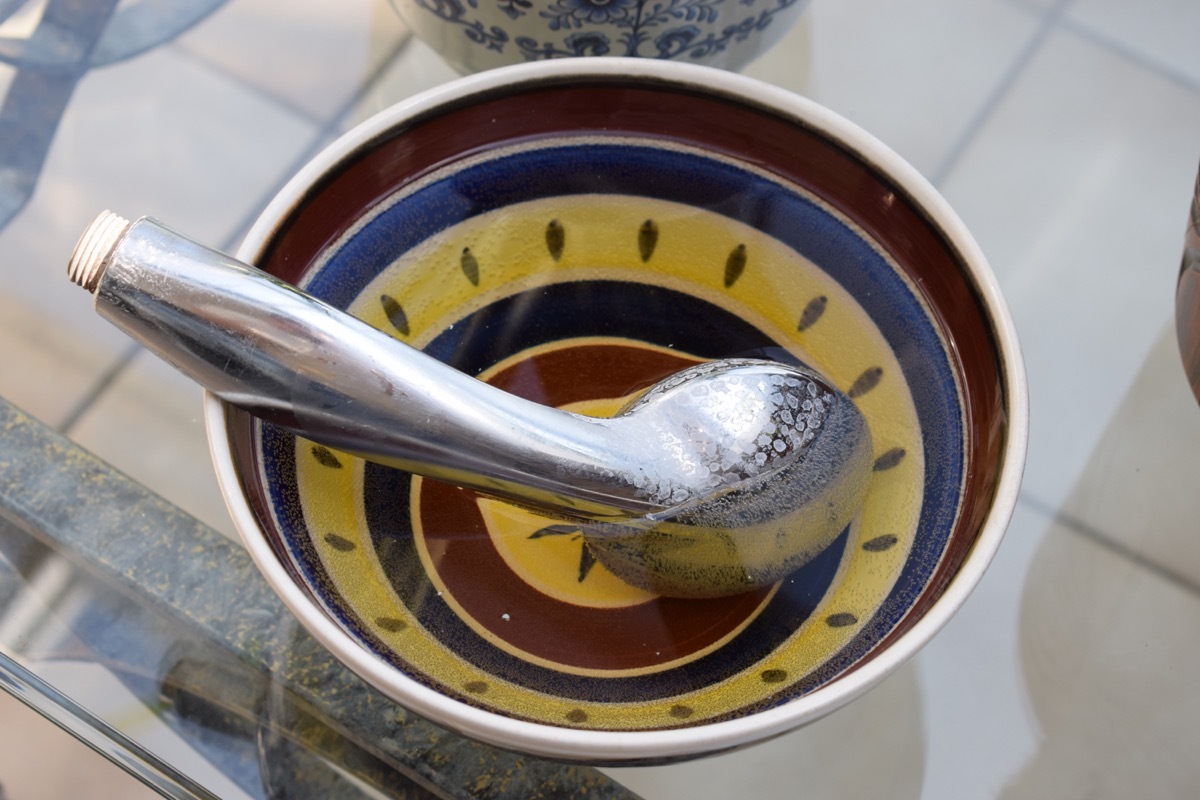 Shower head in bowl of cleaning product