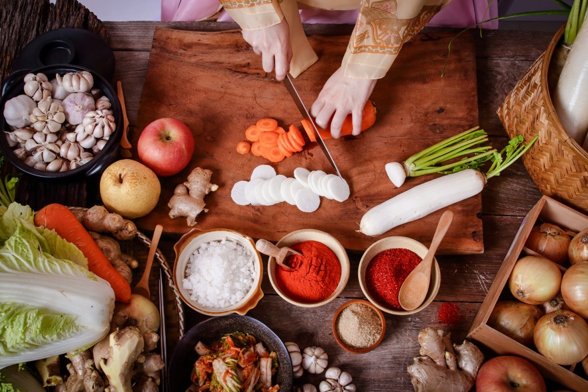 person preparing traditional korean food from an aerial view with bowls of seasonings and vegetables in front of them