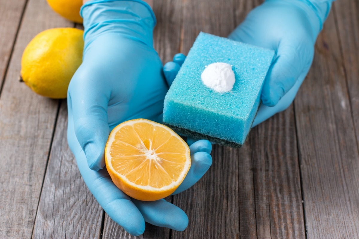 gloved hands holding sponge and lemon