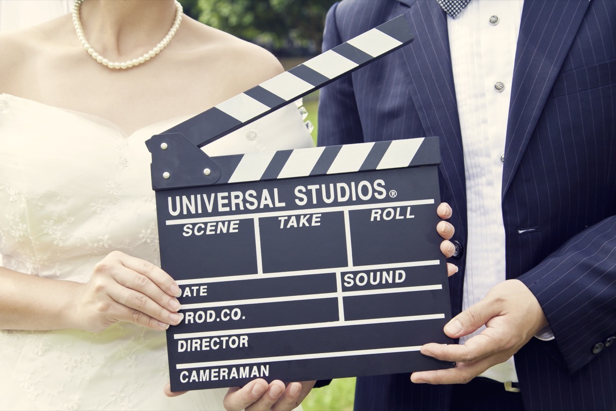 bride and groom holding a clapperboard