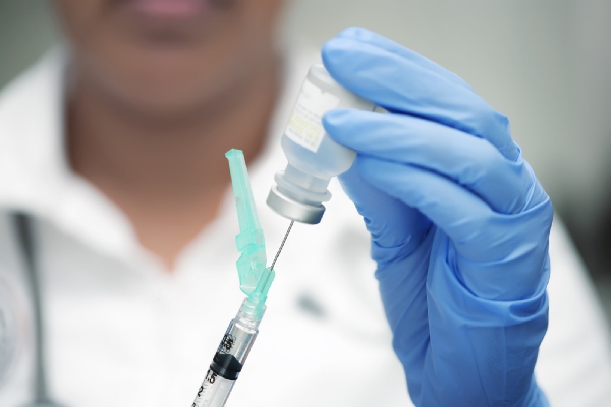 close up of doctor using needle to draw out vaccine