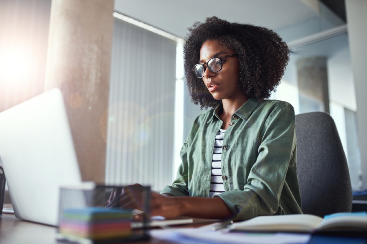 black woman typing on her laptop at an office