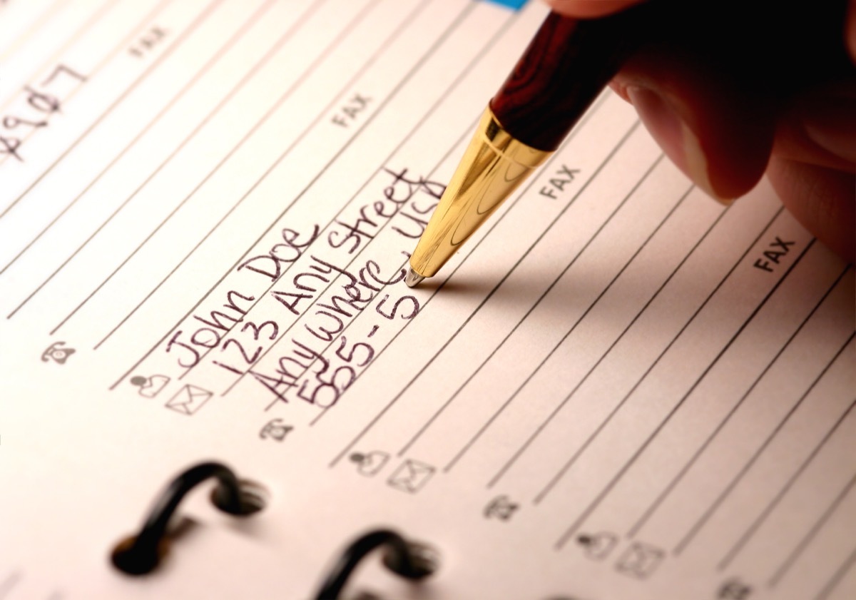 woman writing down important phone numbers in address book