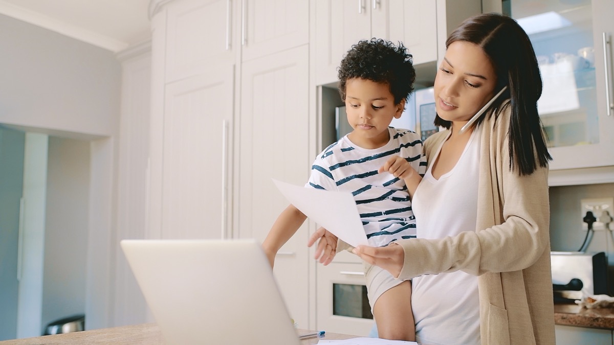 Cropped shot of an attractive young mother holding her son while calculating her finances in the kitchen