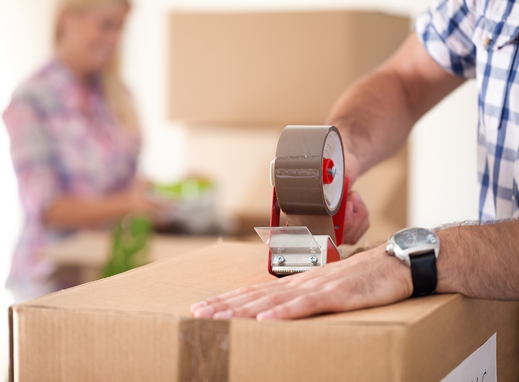 man's hands are shown taping up cardboard box, state fact about New York