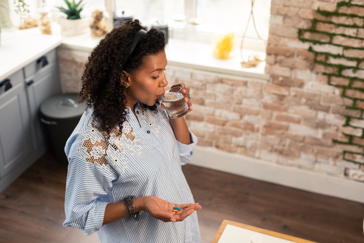 Woman taking vitamins or pills with water