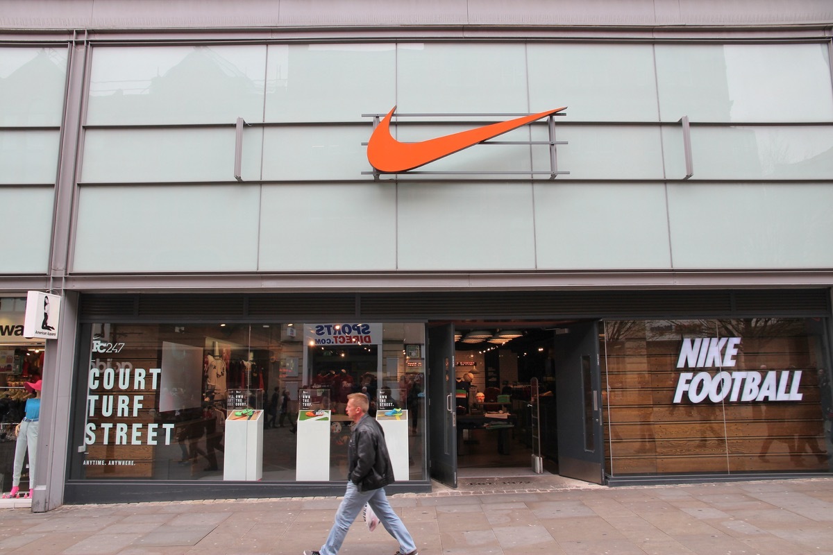 Man walks by Nike sports fashion store in Manchester, UK. Nike brand was valued at 19 billion USD in 2014.