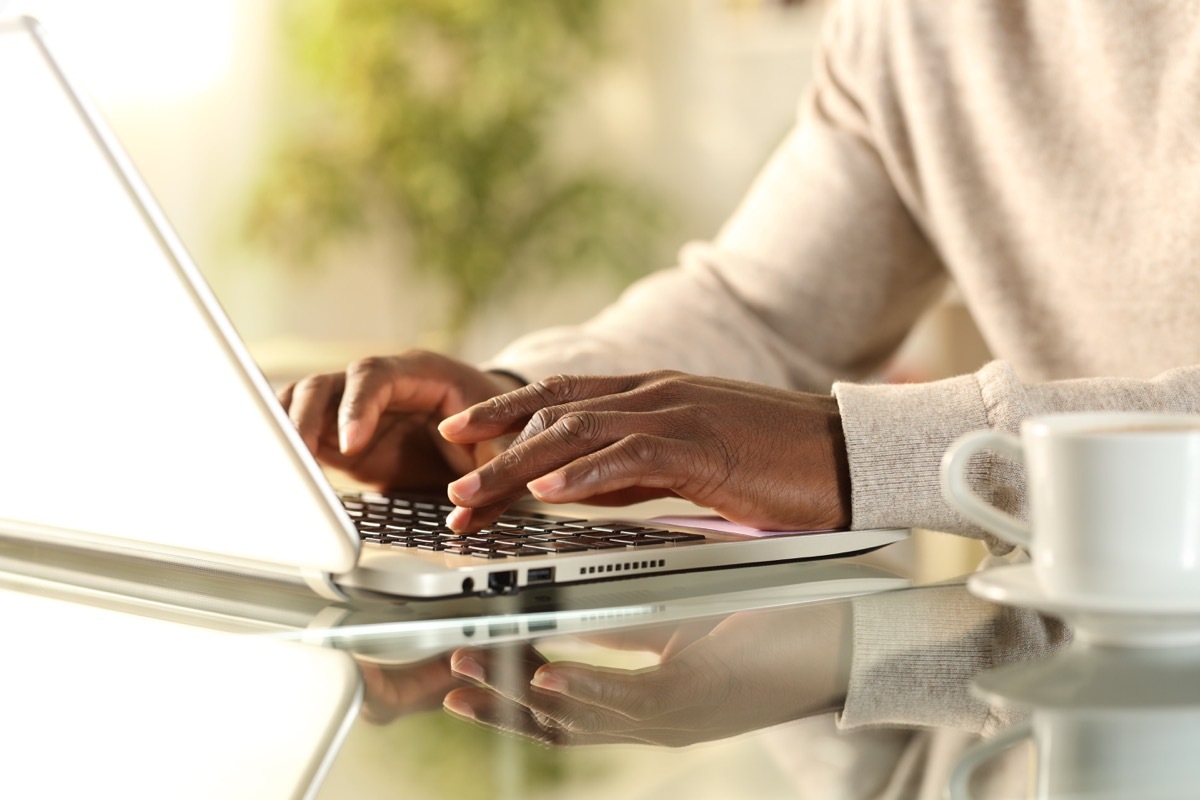 man hands typing on a laptop at home