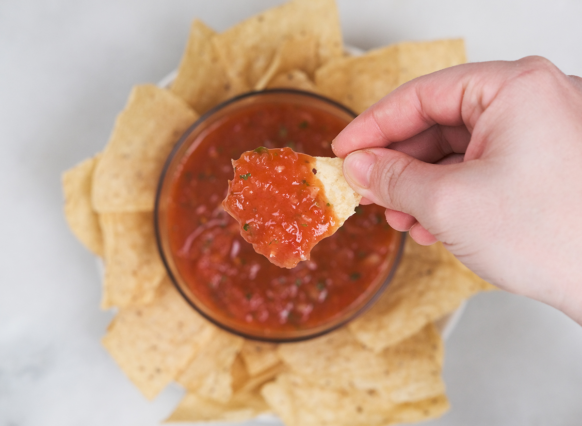 dipping chips into a bowl of salsa