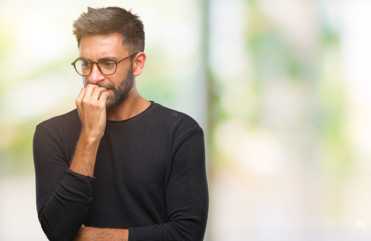 latino man biting his nails and looking nervous