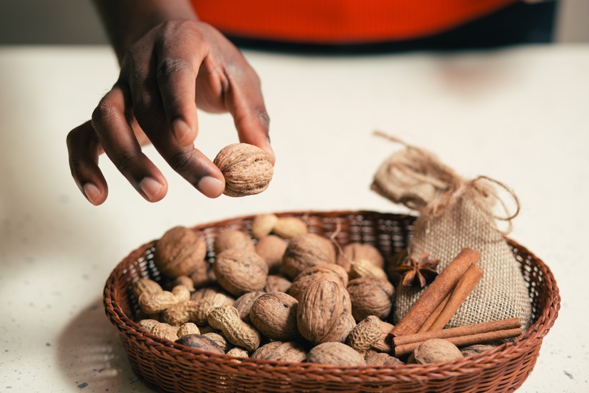 woman picking up a nut from a basket of nuts