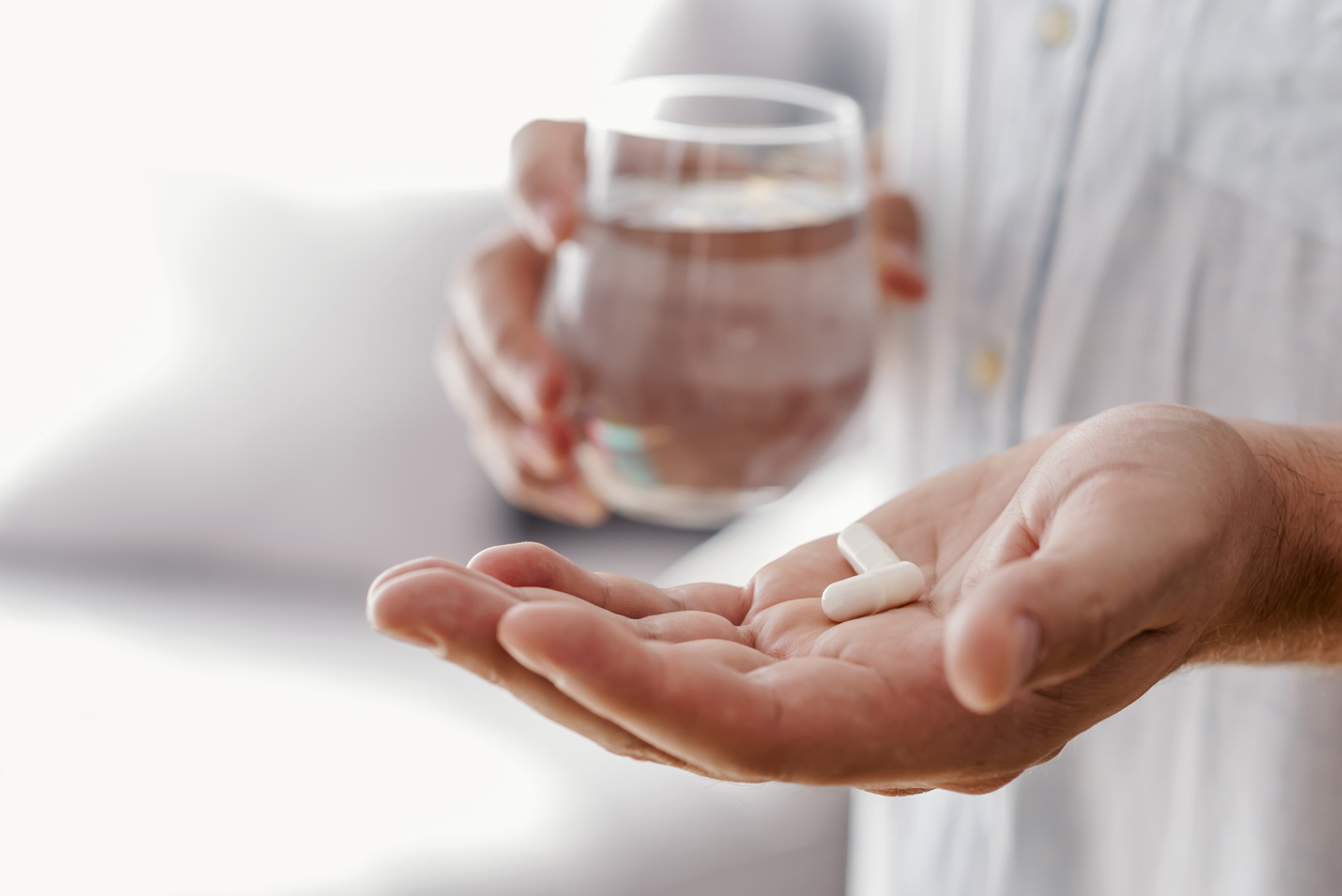 Hands holding pills and a glass of water. 