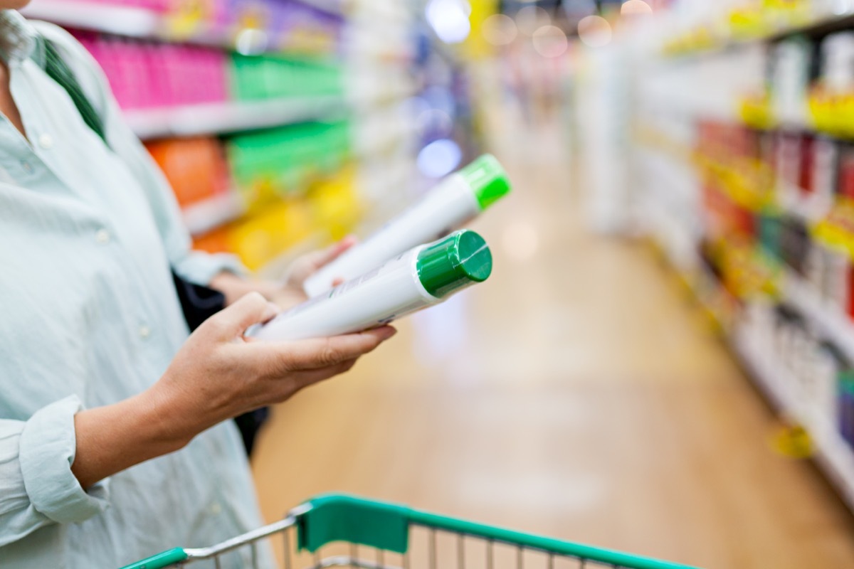 Woman pushing a shopping cart in the supermarket, focus on woman