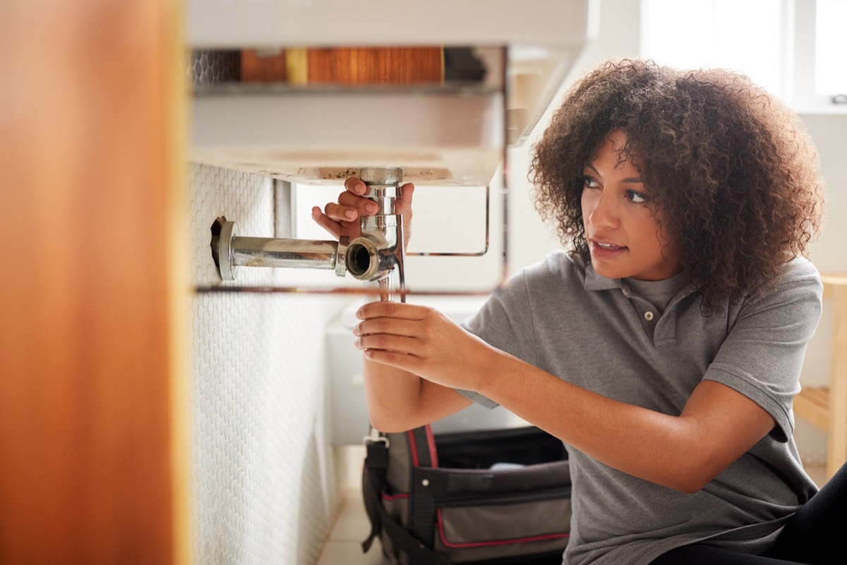 young black woman fixing sink